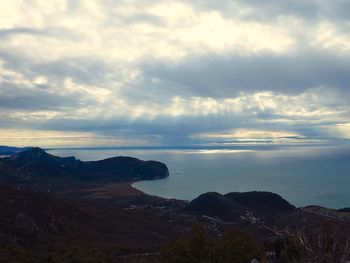 Scenic view of sea and mountains against cloudy sky