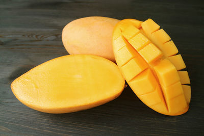 Fresh ripe mango cut in half and crosswise cut with a whole fruit on black background