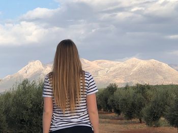 Rear view of woman looking at mountains against sky