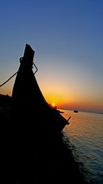 Silhouette person in sea against sky during sunset