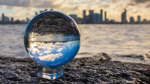 Close-up of crystal ball on beach against sky