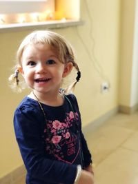 Portrait of cute girl smiling while standing at home