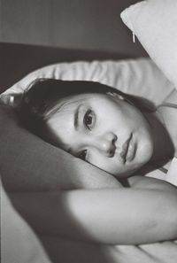 Close-up portrait of young woman relaxing on bed at home