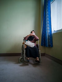 Full length of woman sitting on wall at home