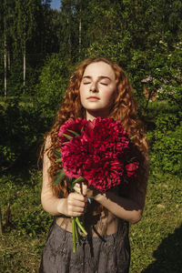 Girl holding floral bouquet while standing outdoors