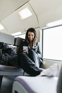 Smiling young woman on train looking on cell phone