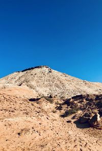 Low angle view of rocky mountain against clear blue sky