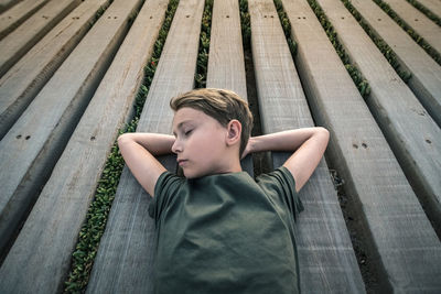High angle view of boy lying on wooden floor