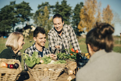 Male and female farmers using mobile phone with organic vegetables on table