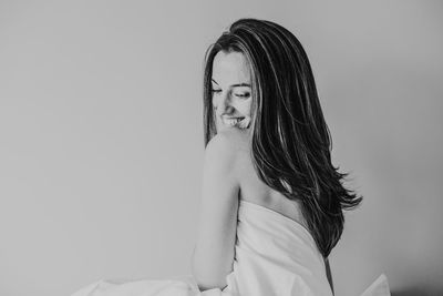 Smiling woman with blanket sitting against wall