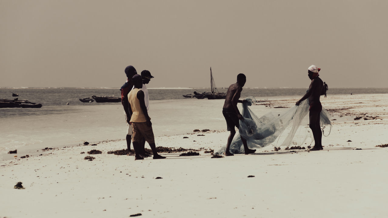 PEOPLE ON BEACH AGAINST SKY