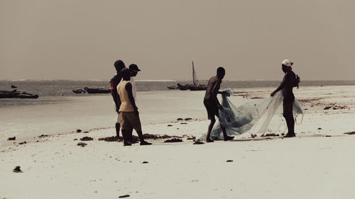 People on beach against clear sky