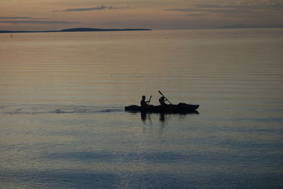 Silhouette people on boat in sea against sky during sunset