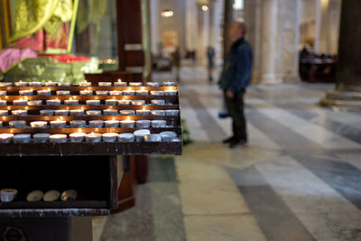 Lit tea light candles against man standing in church