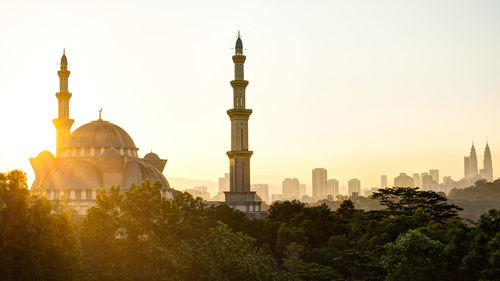 Silhouette mosque against clear sky in city during sunset