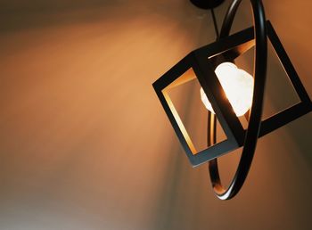 Close-up of illuminated lamp hanging against wall
