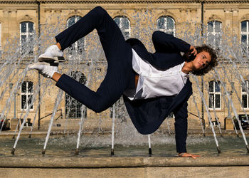 Full length of man jumping against fountain