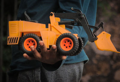 Midsection of man holding bulldozer toy outdoors