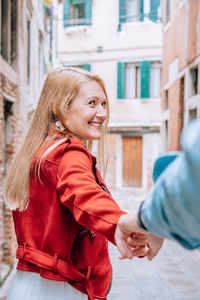 Couple holding hands while standing against buildings