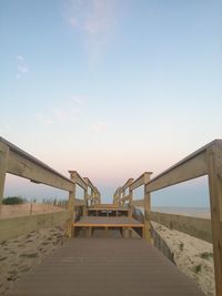 Wooden boardwalk at beach against sky