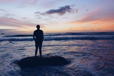 Rear view of silhouette man standing on beach during sunset