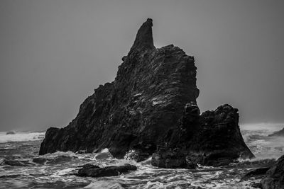 Rock formation on beach against clear sky