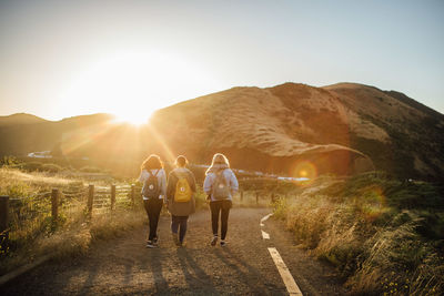 Rear view of people walking on road against mountain