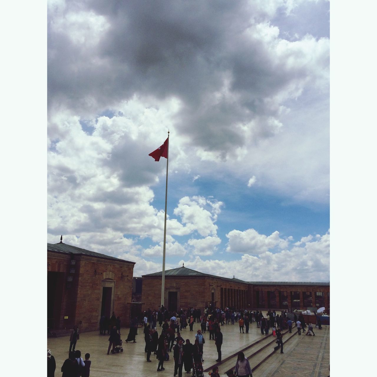 large group of people, sky, men, person, building exterior, architecture, built structure, lifestyles, cloud - sky, flag, cloud, leisure activity, cloudy, transfer print, crowd, mixed age range, national flag, walking, city