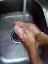 Cropped image of hand touching water from faucet in bathroom