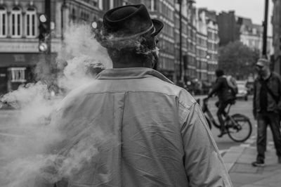 Rear view of man smoking on city street