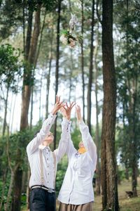  prewedding with white concept and throwing flowers.rear view of woman standing in forest, 