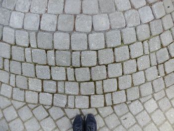 Low section of man standing on cobblestone