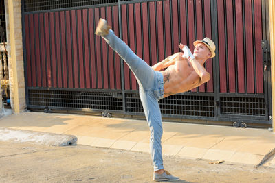 Full length of shirtless man exercising outdoors