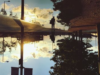 Silhouette man by trees against sky during sunset