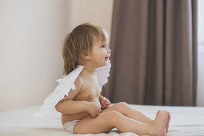 Young woman sitting on bed at home