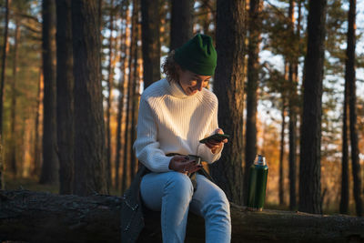 Cheerful woman laugh reading text message or scroll social media walking in autumn forest on weekend