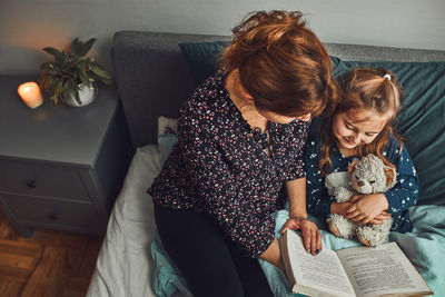 Mother reading book her daughter in bed before going to sleep. reading stories before sleep. bedtime