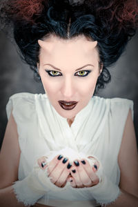 Digital composite image of horned woman with make-up holding white powder