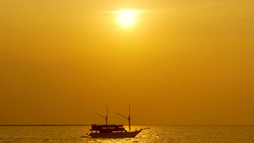 Silhouette sailboat in sea against sky during sunset