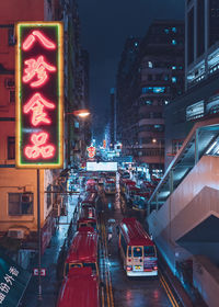 Illuminated street amidst buildings in city at night