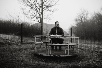 Man sitting on a carousel on a playground 