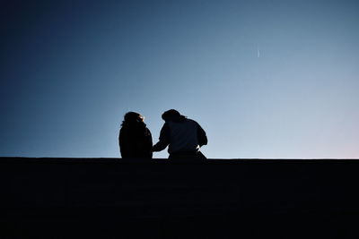 Silhouette people sitting against clear sky