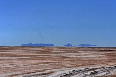 Scenic view of desert against clear blue sky