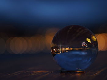 Close-up of crystal ball on beach against sky during sunset