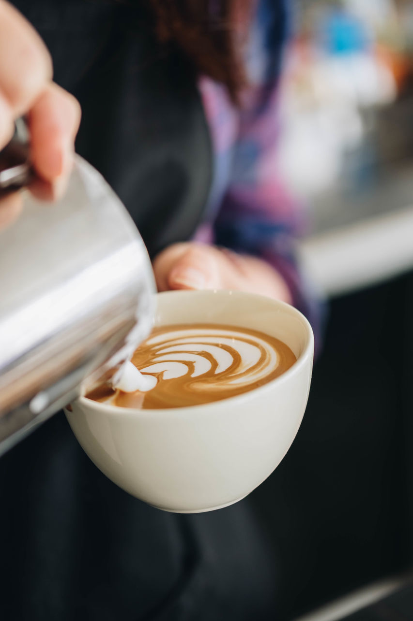 CLOSE-UP OF HAND HOLDING CAPPUCCINO