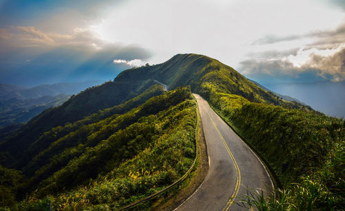 Empty road leading towards mountains against sky