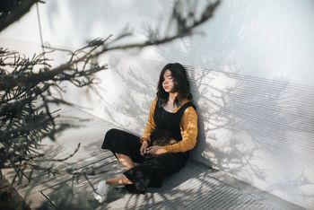 PORTRAIT OF SMILING WOMAN SITTING ON TREE