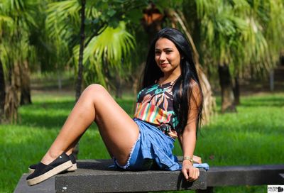 Young woman sitting on plant against trees