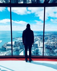 Rear view of man looking at cityscape against sky