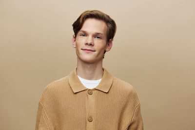 Portrait of young man standing against black background